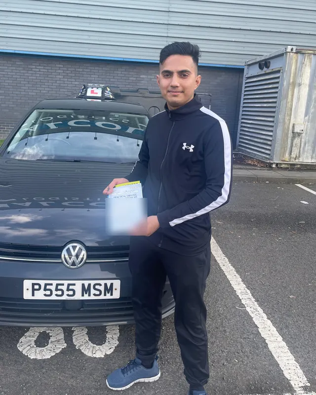 Saleh Mustafa holding his pass certificate beside the MSM car after passing at Paisley