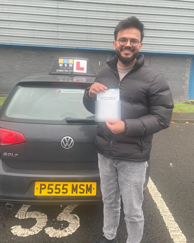Umar holding his pass certificate beside the MSM car after passing at Paisley