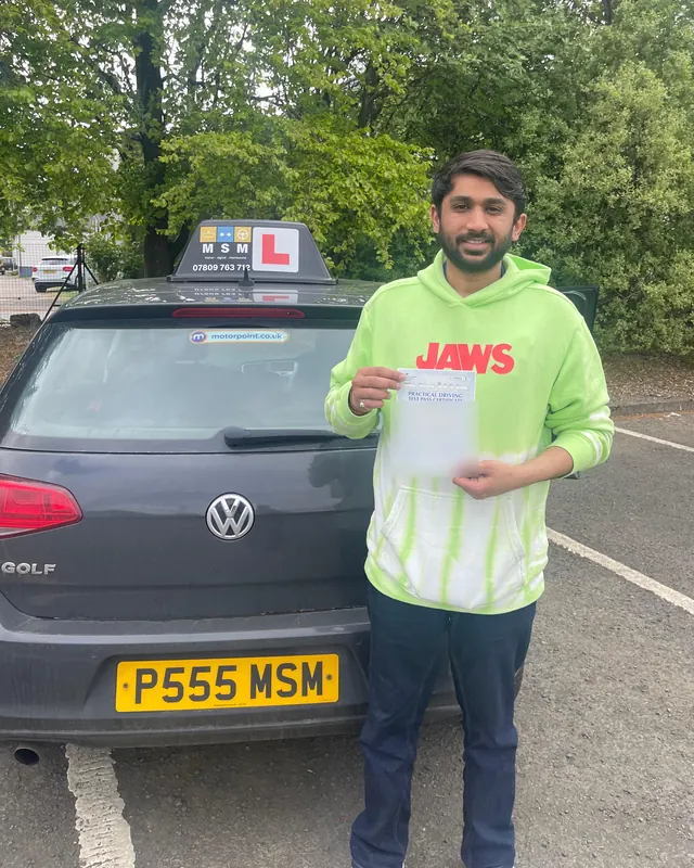 Raval holding his pass certificate beside the MSM car after passing at Shieldhall